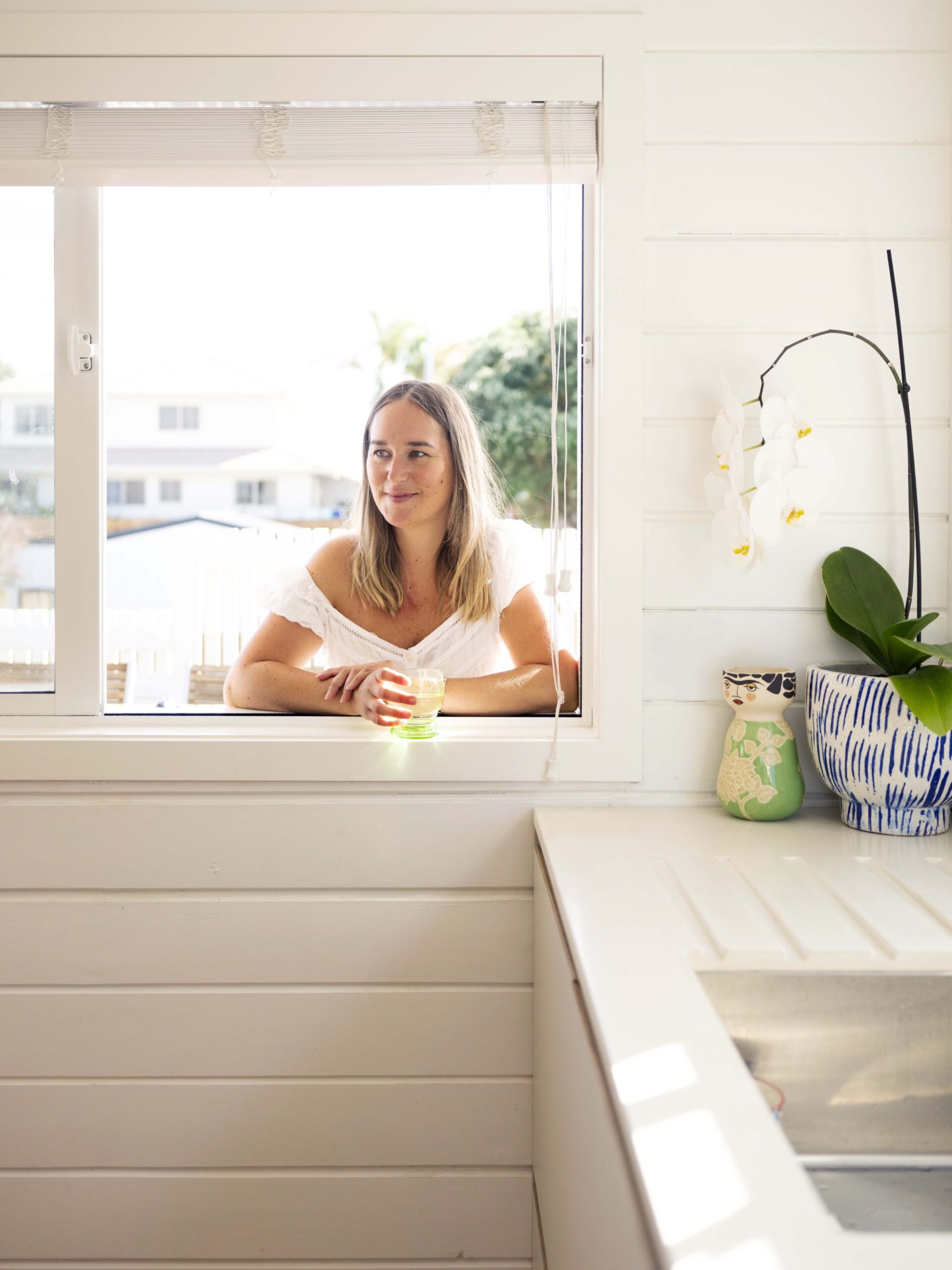 Renée Reichmuth standing at kitchen window holding green glass