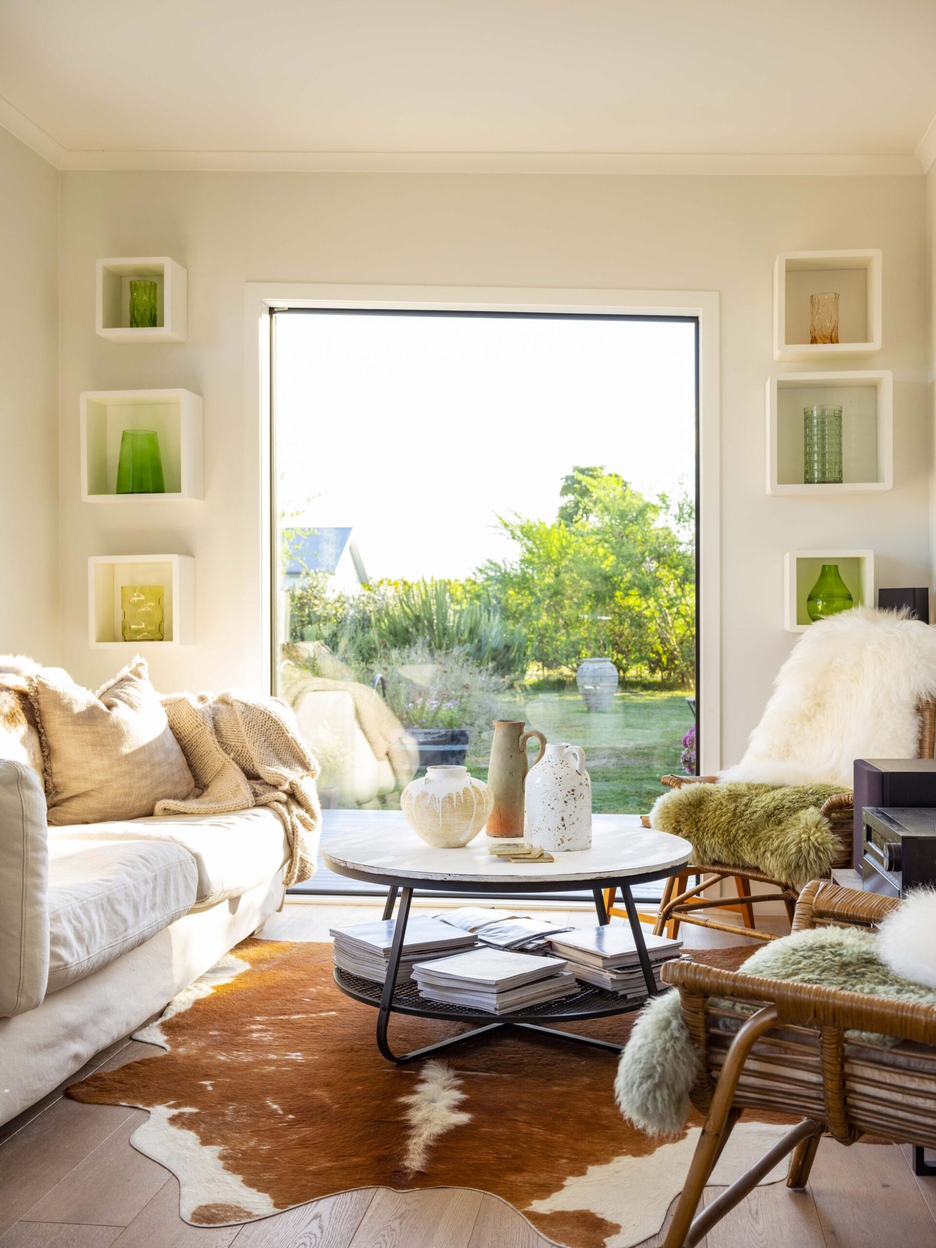 Cosy lounge with big window, cowhide rug and sheepskin throws on the furniture