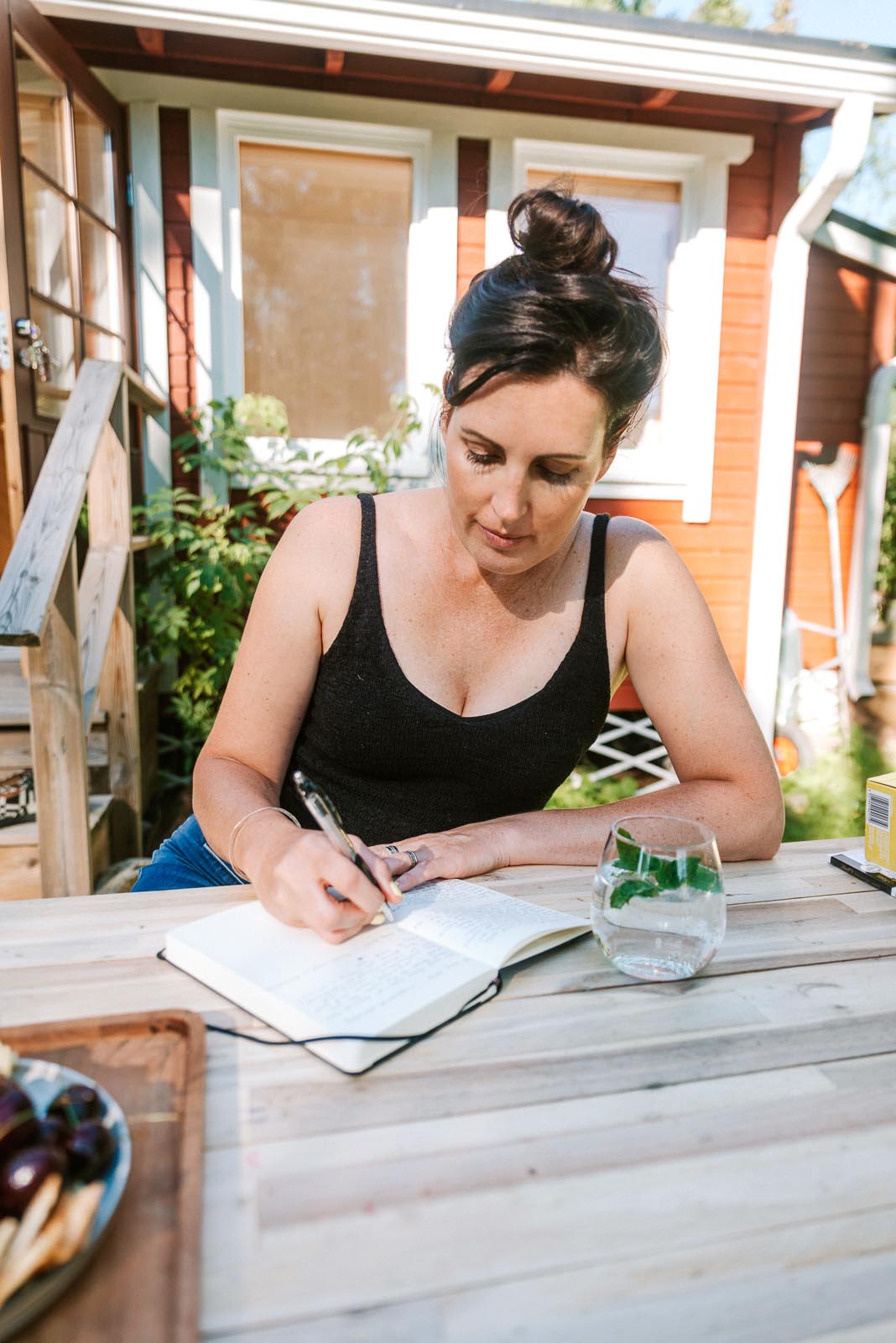 Melanie Dower sitting outside a cabin at a table writing in a book