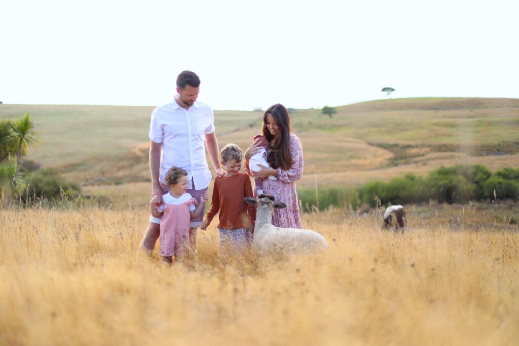 Michael and Beccy Beavis standing in a yellow field with a sheep and their children