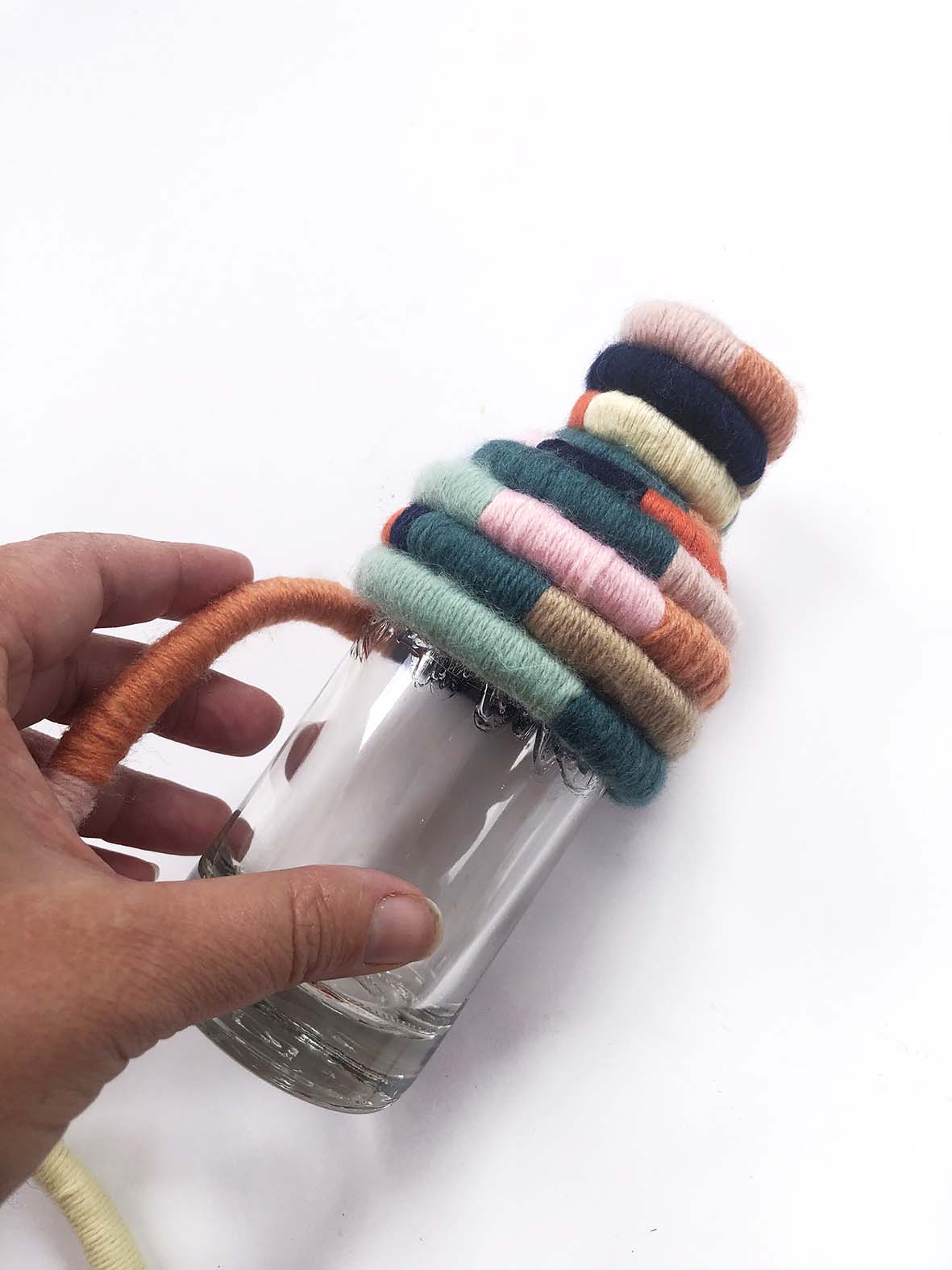 A bottle wrapped in rainbow cord