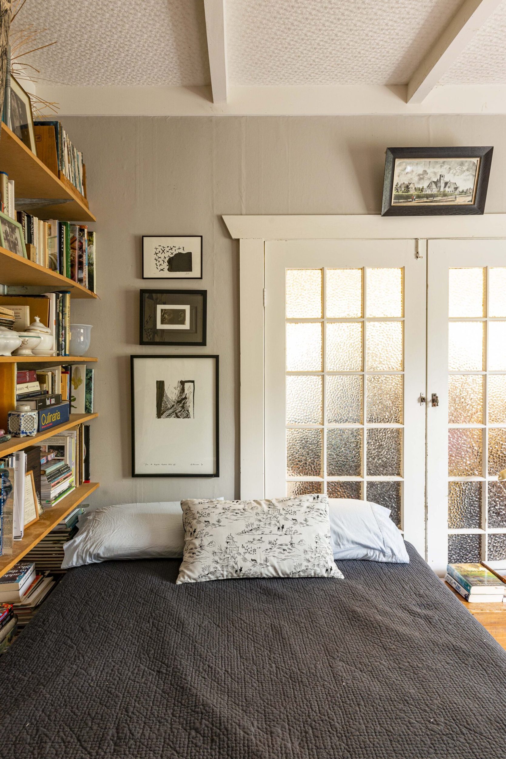 A grey room with white French doors and shelves filled with books