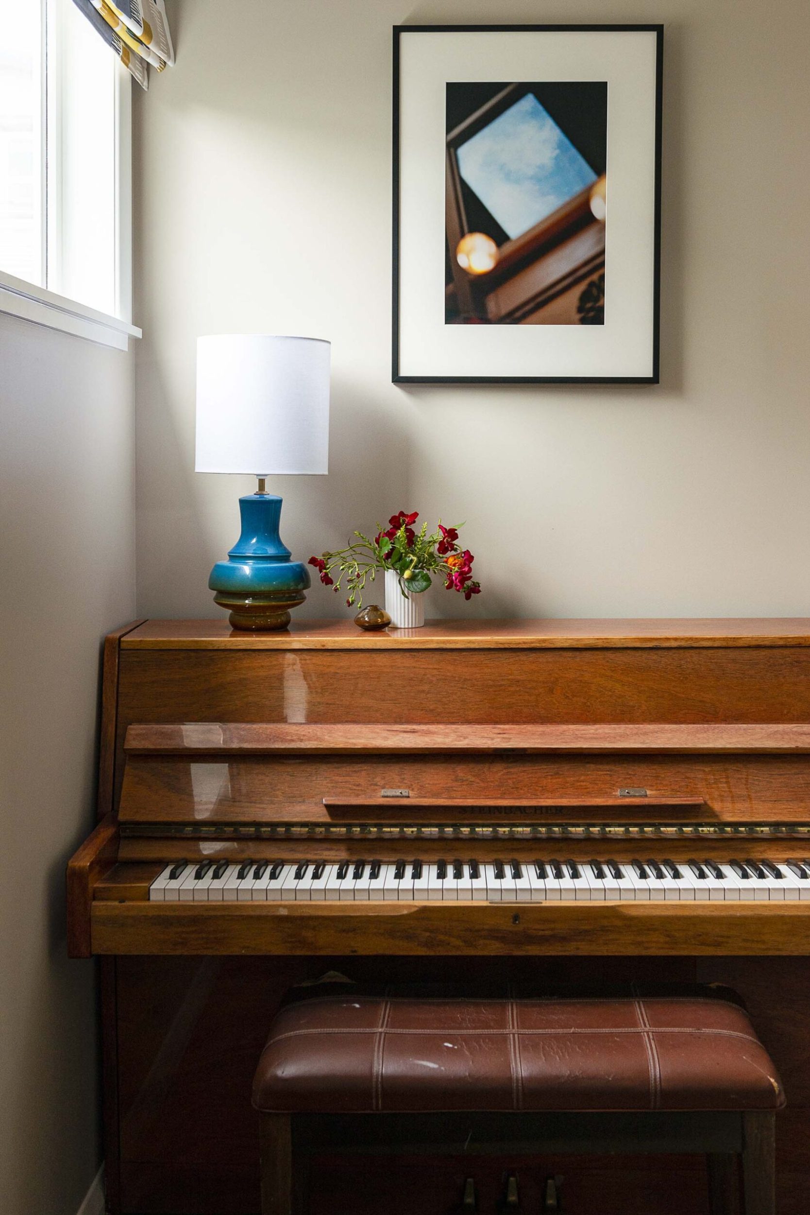 Piano with blue lamp and small white vase with flowers
