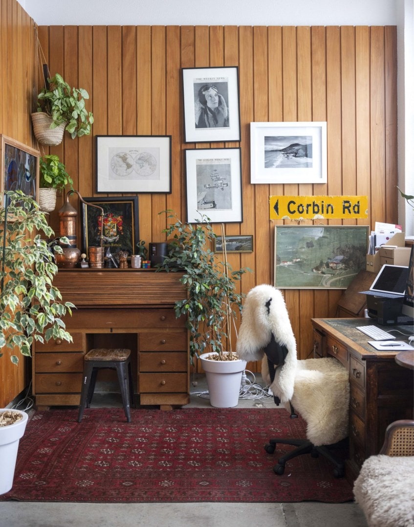 Room with tall wooden walls, green plants and assorted hanging art