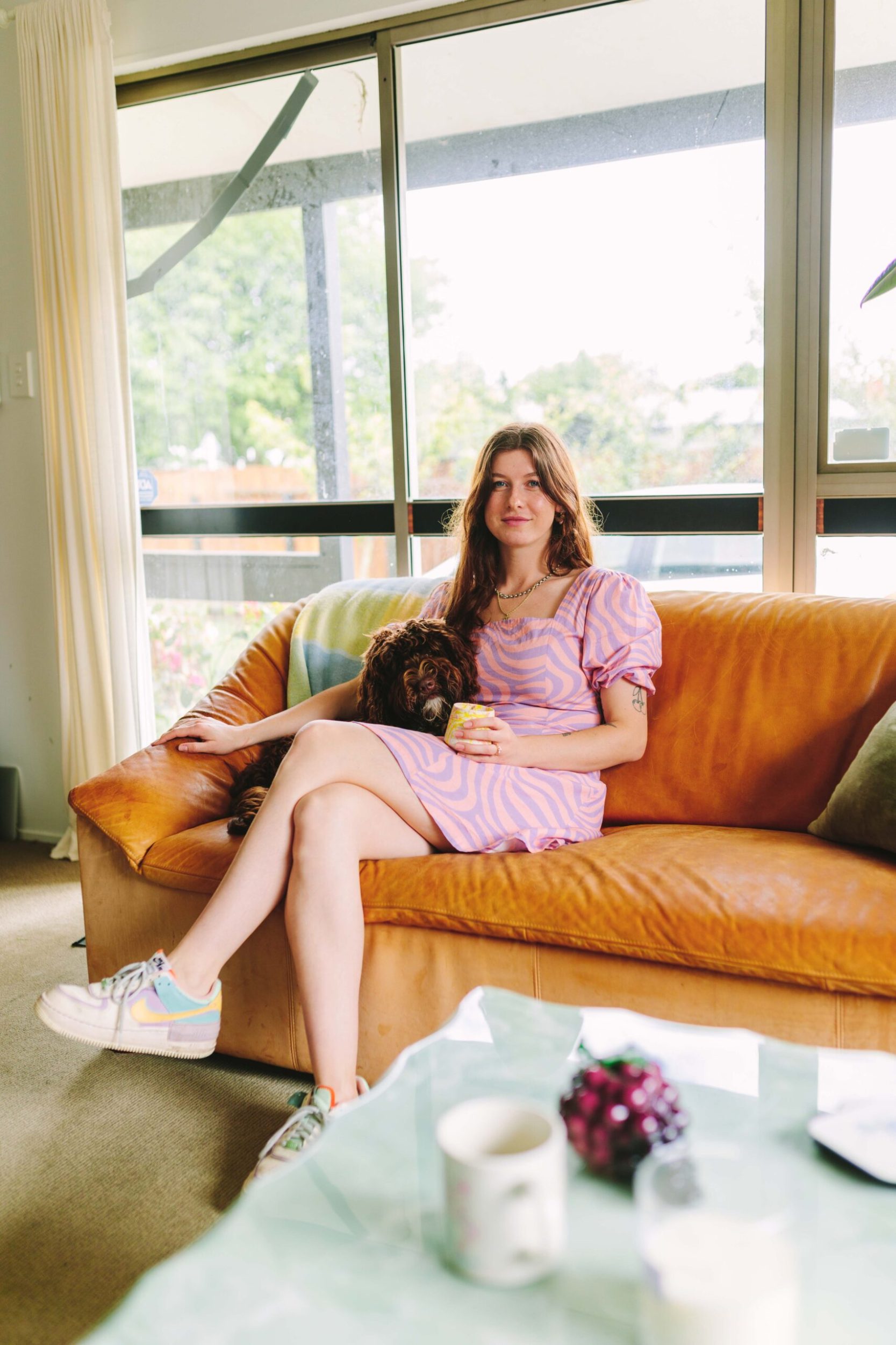 Tiffany Clayton sitting on brown couch with her dog 