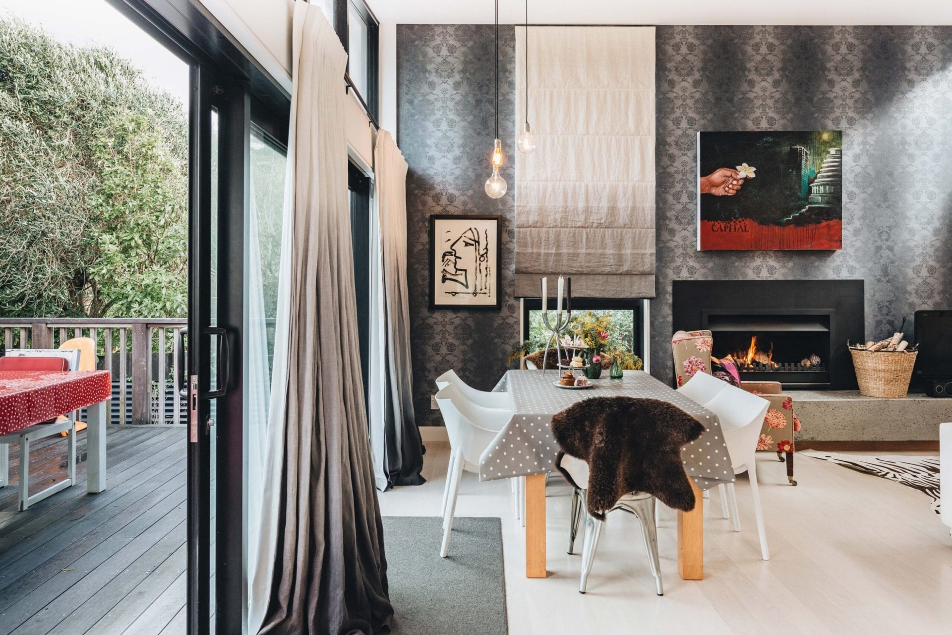 dining room with grey wallpaper on the back wall, large table with grey table cloth and doors opening onto a deck