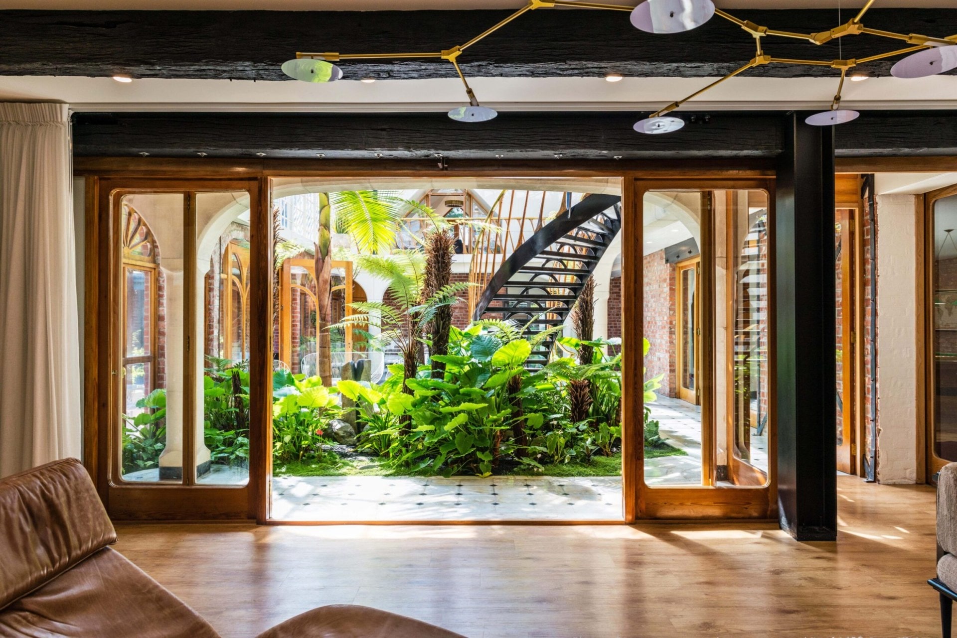 Open glass windows facing large leafy courtyard at The Britten Stables