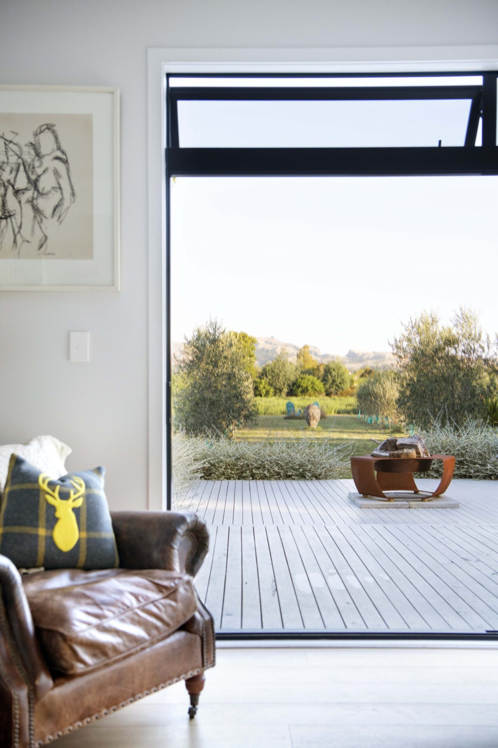 A large open door facing out into a large yard and black deck