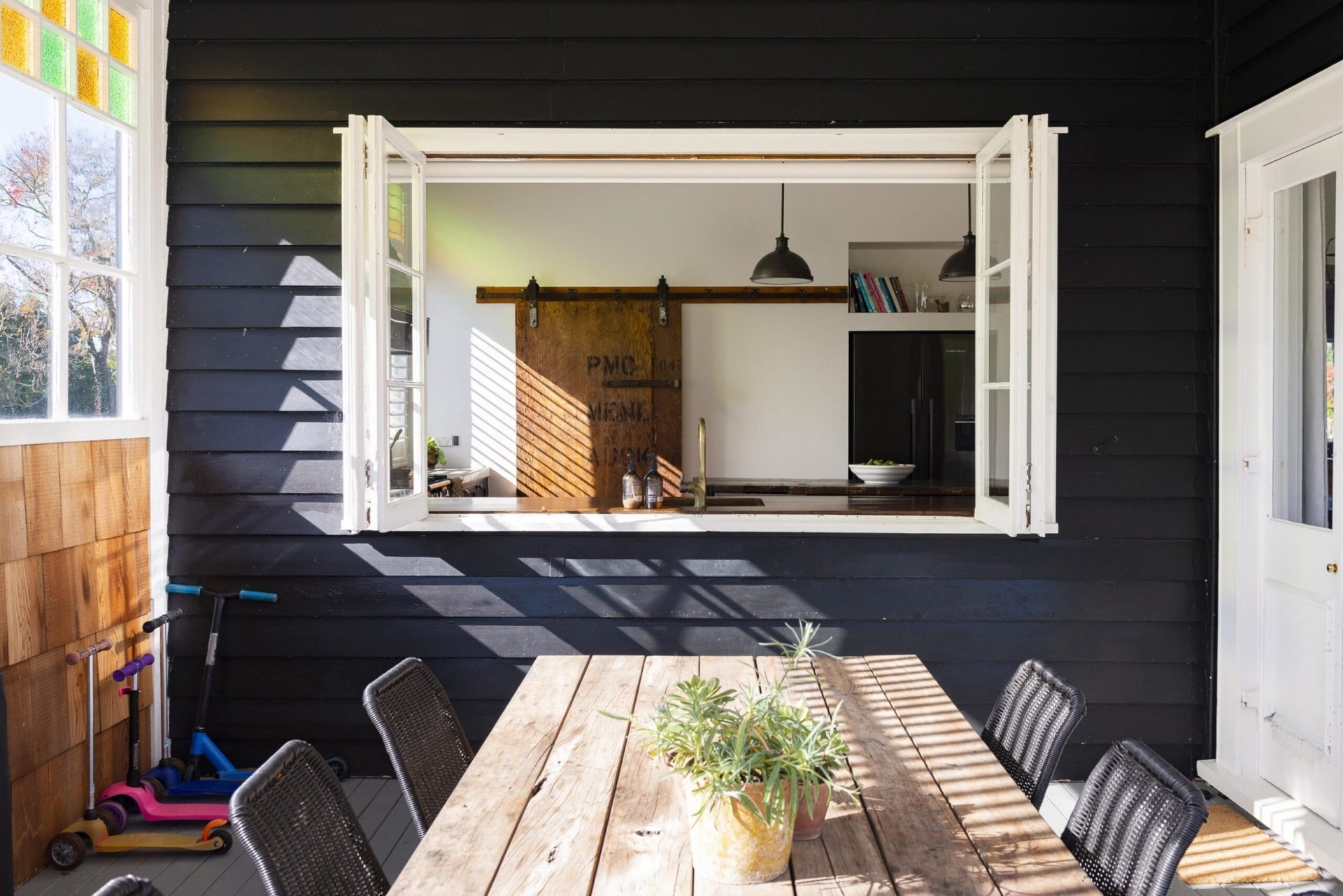An outdoor wood table with an open window facing the kitchen