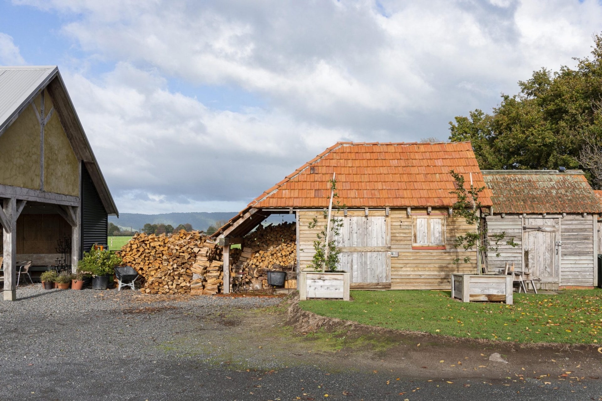 A wood cottage with an orange roof and large pile of cut firewood