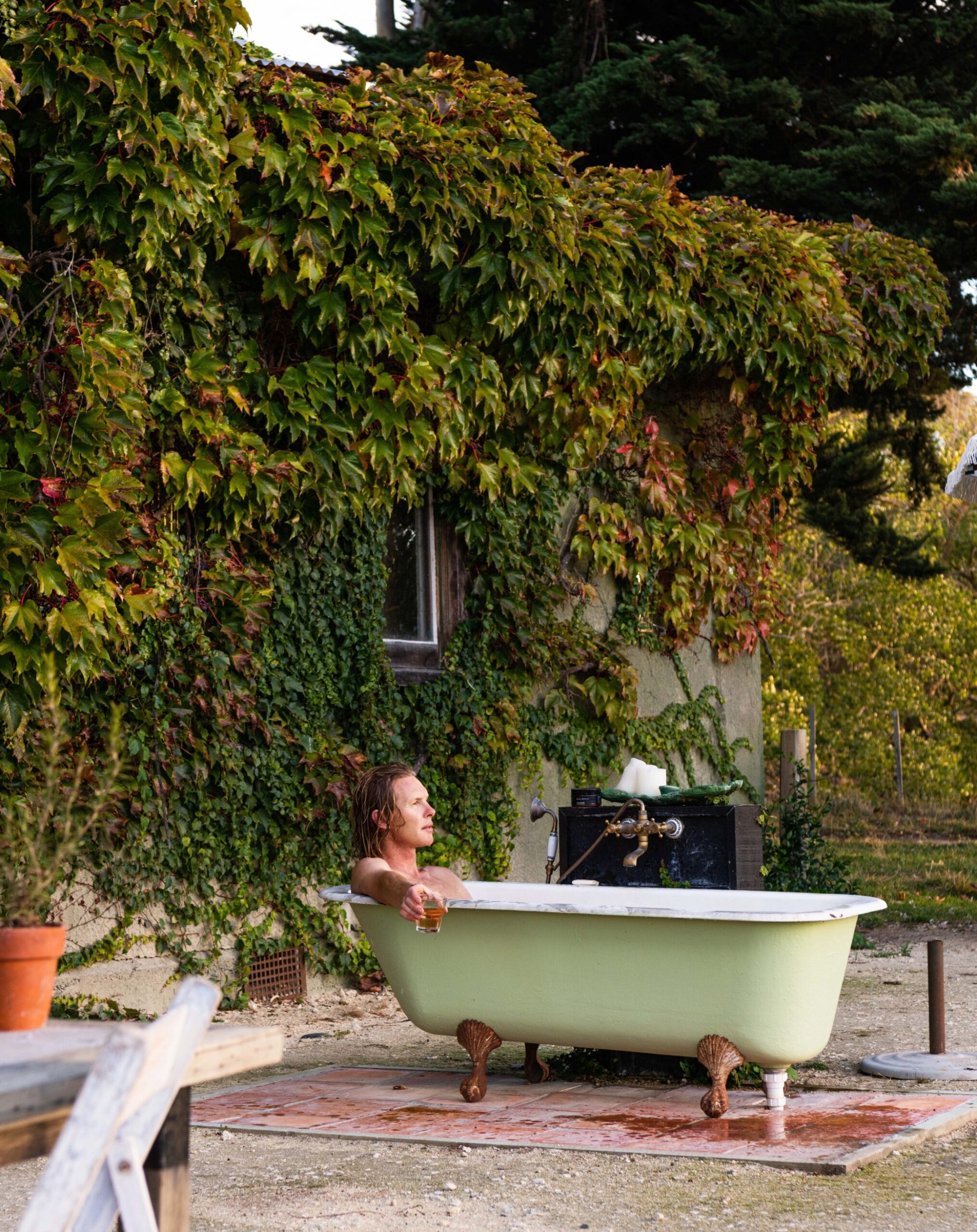 George Gaddum lying in green outdoor claw foot bath tub 