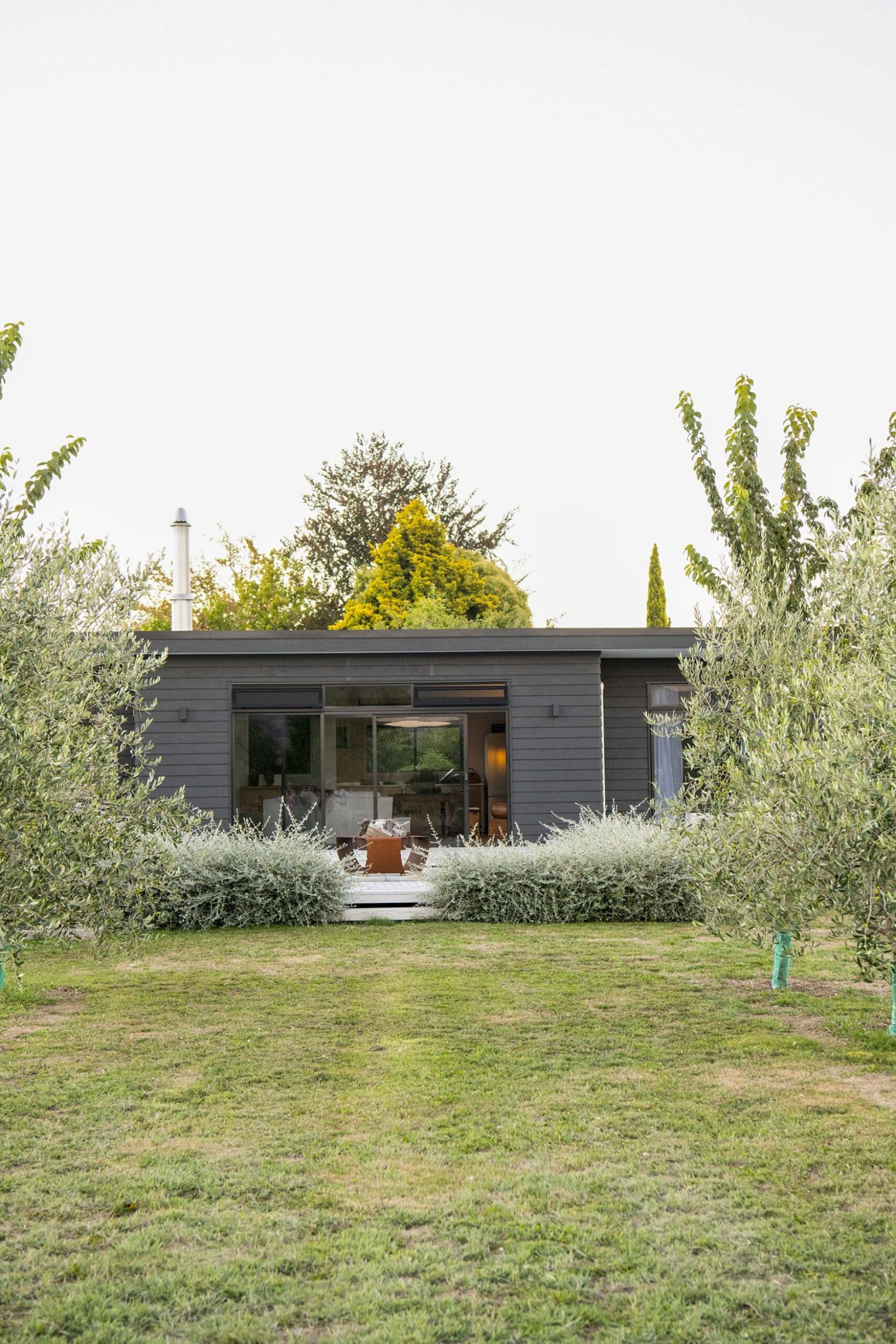 A large black home on a large green yard