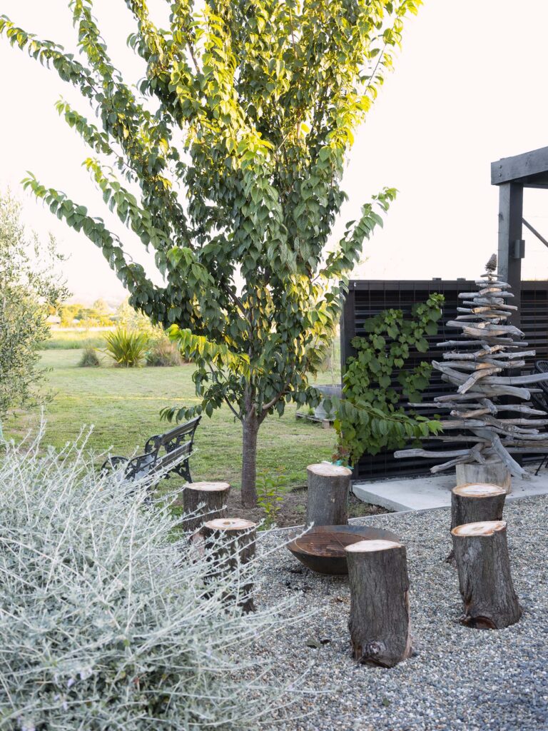An outdoor sitting area with wooden log seats and fire bowl