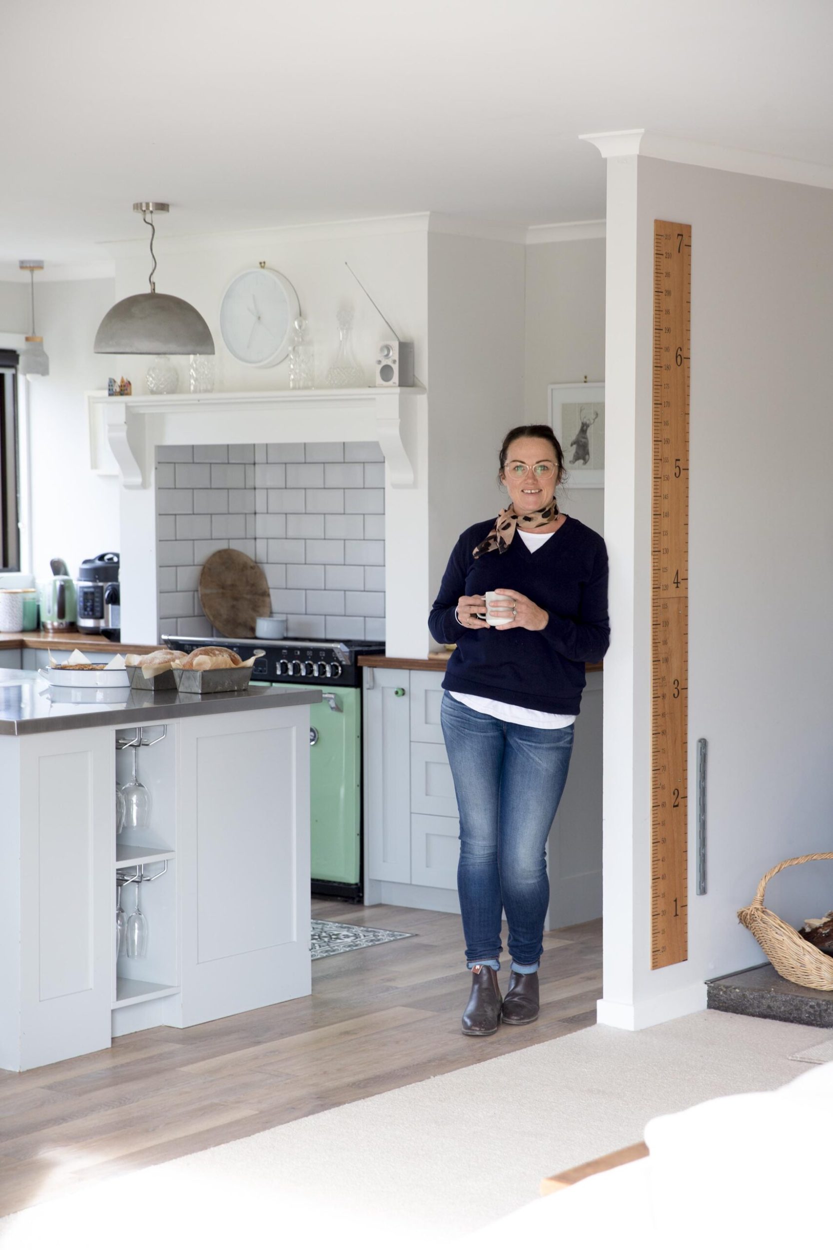 Philippa Cameron leaning against a kitchen wall holding a cup of tea