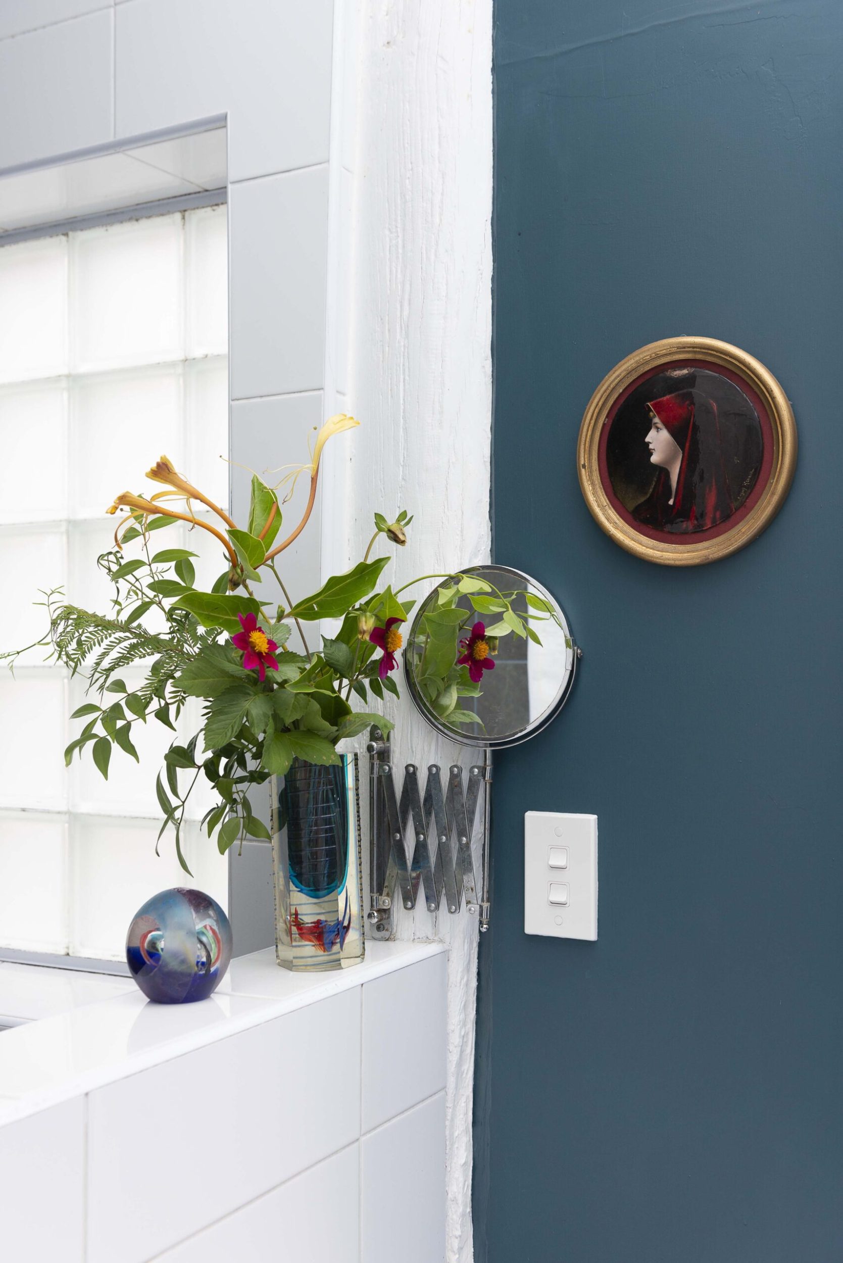 Glass vase filled on white bannister in front of a blue wall