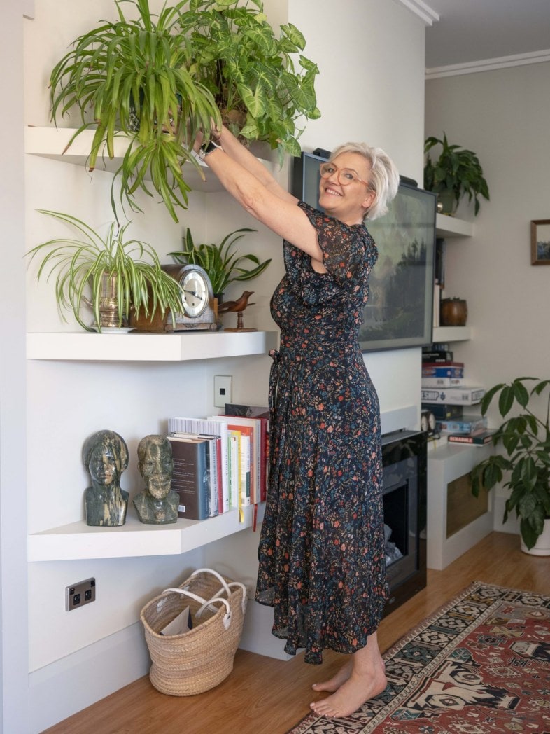Wendy Nowell-Usticke watering plants in tall shelf