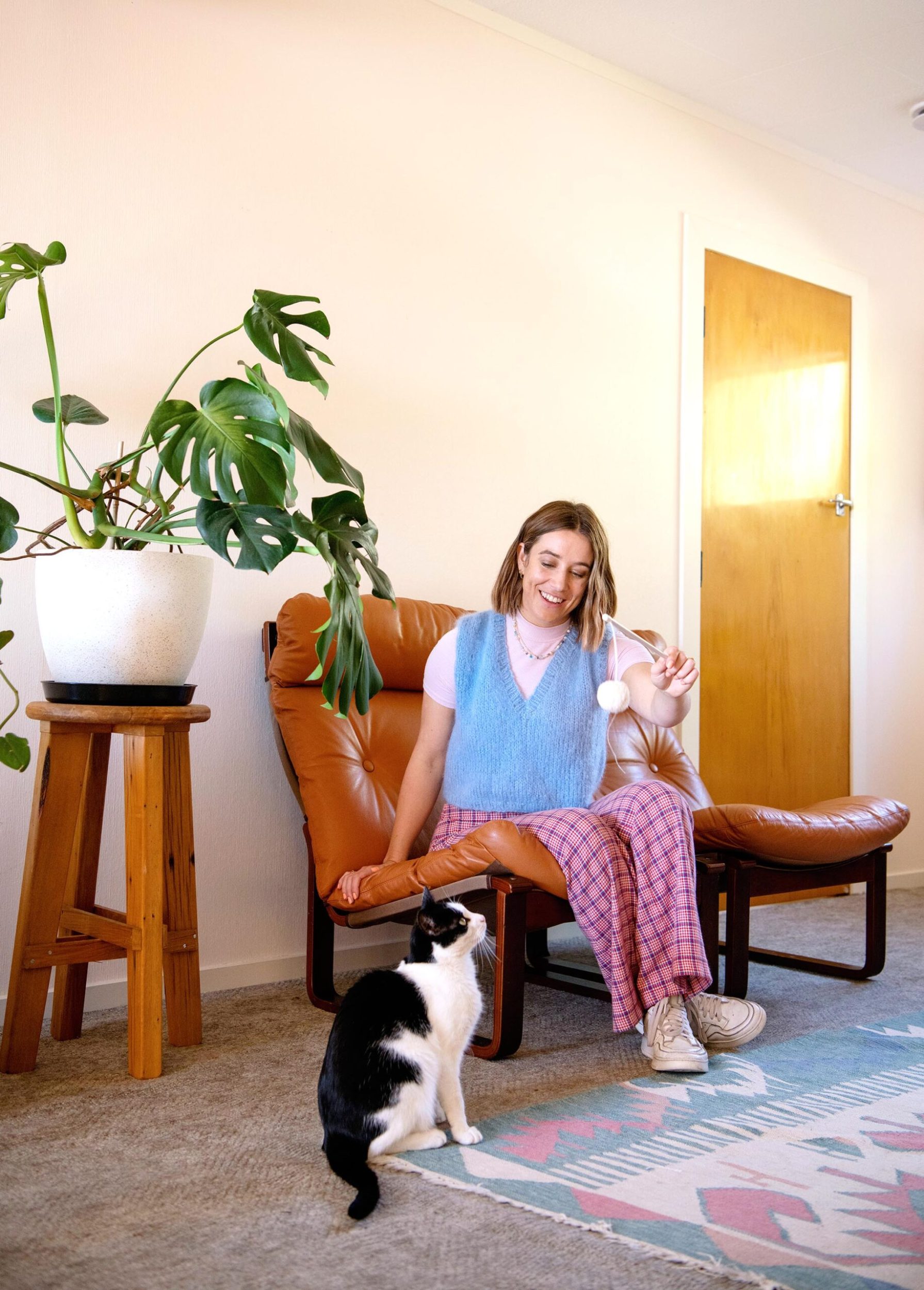 Danni Duncan sedí v hnědém křesle v obývacím pokoji a hraje si s černobílou kočkou Stanley