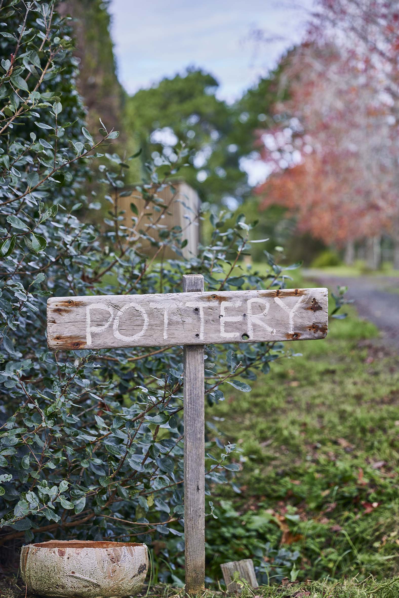 A small brown wood sign with lettering saying POTTERY