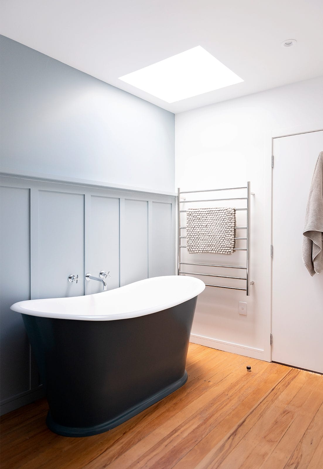 Bathroom with freestanding bathtub in front of powder blue feature wall 