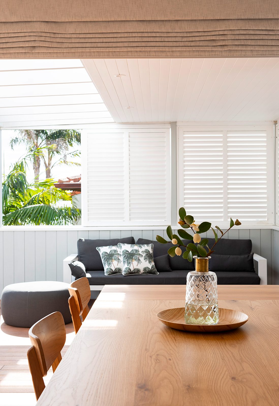 Windows with white wooden shutter with grey couch and timber dining table