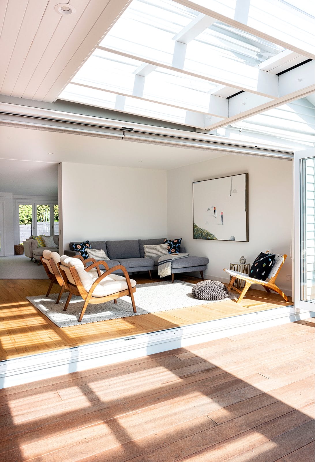 View into living room with doors wide open and grey L-shaped couch