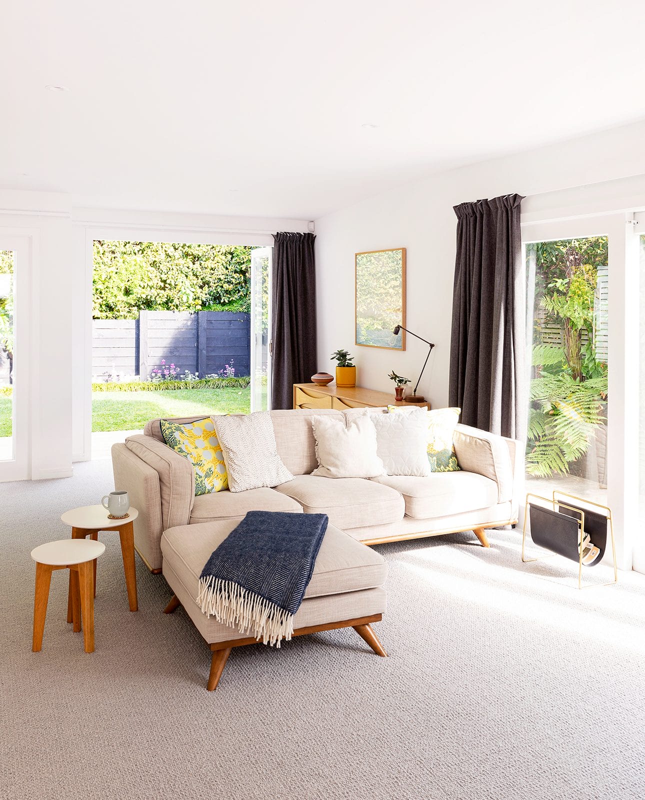 Cream L-shaped couch dressed with cushions and blue blanket