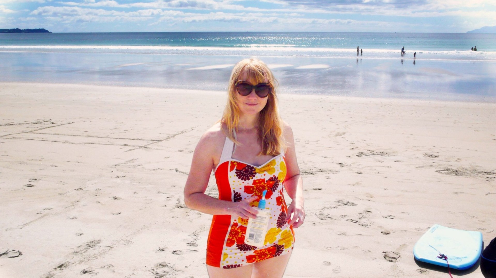 Rachel Clare standing on beach shore wearing patterned red swimsuit