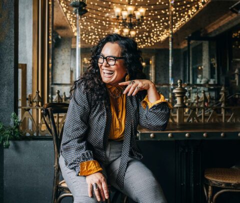 Rachel House sitting by bar wearing yellow top