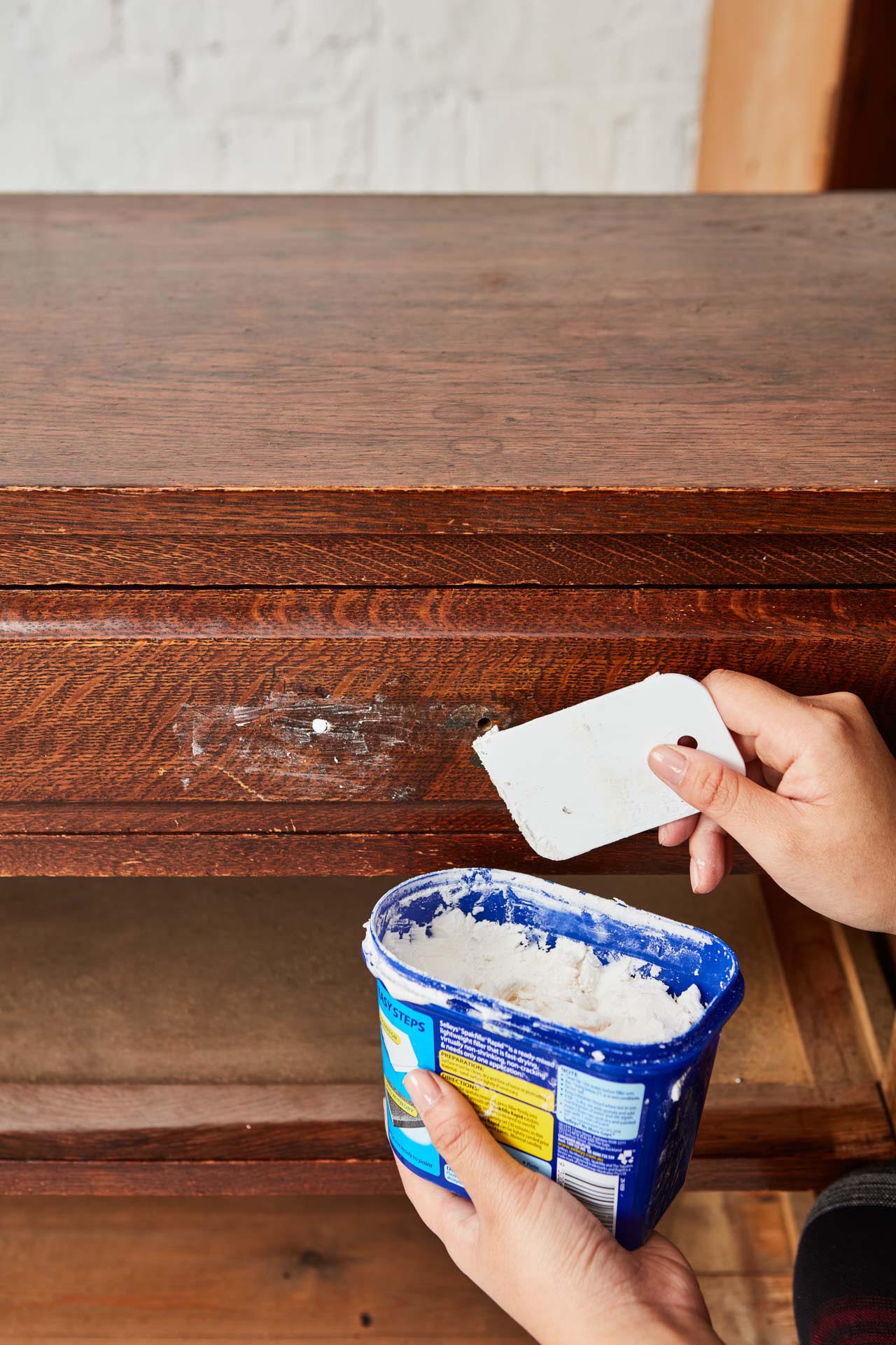 Holes in a vintage chest of drawers being filled with Resene EzyFill Quick.