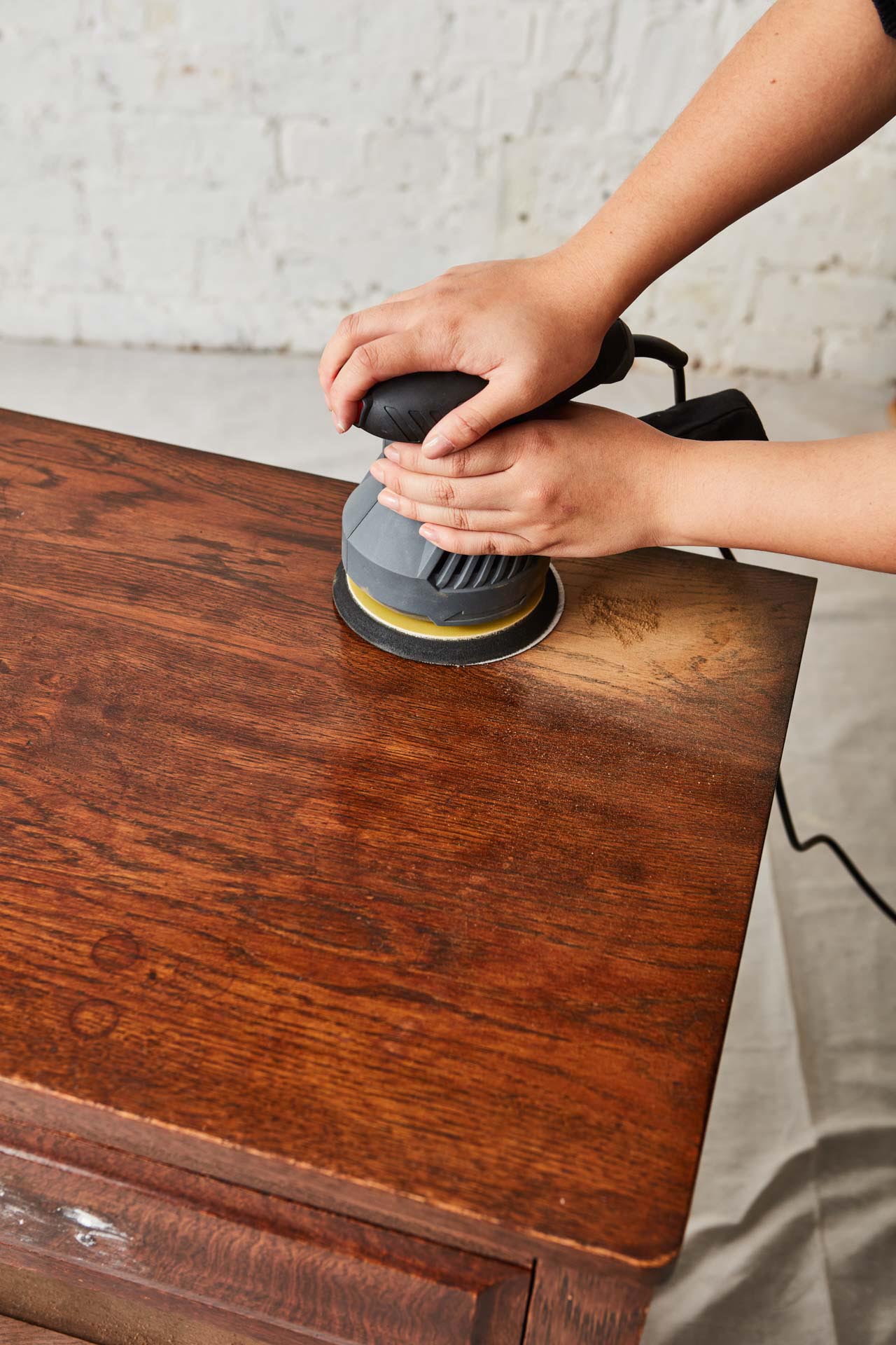 Vintage chest of wooden drawers being sanded with electric sander