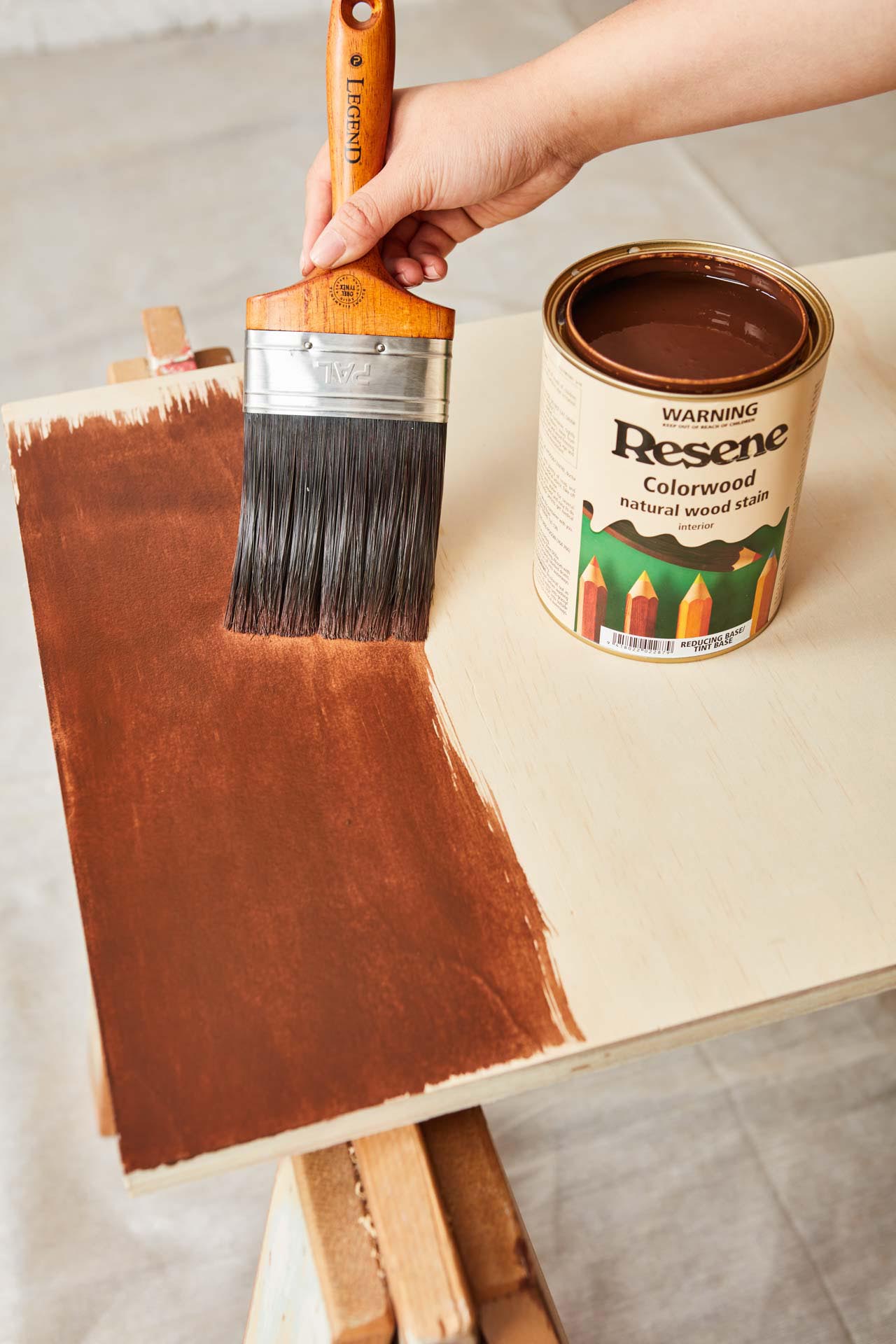 Paint brush staining sheet of ply wood with Resene natural wood stain