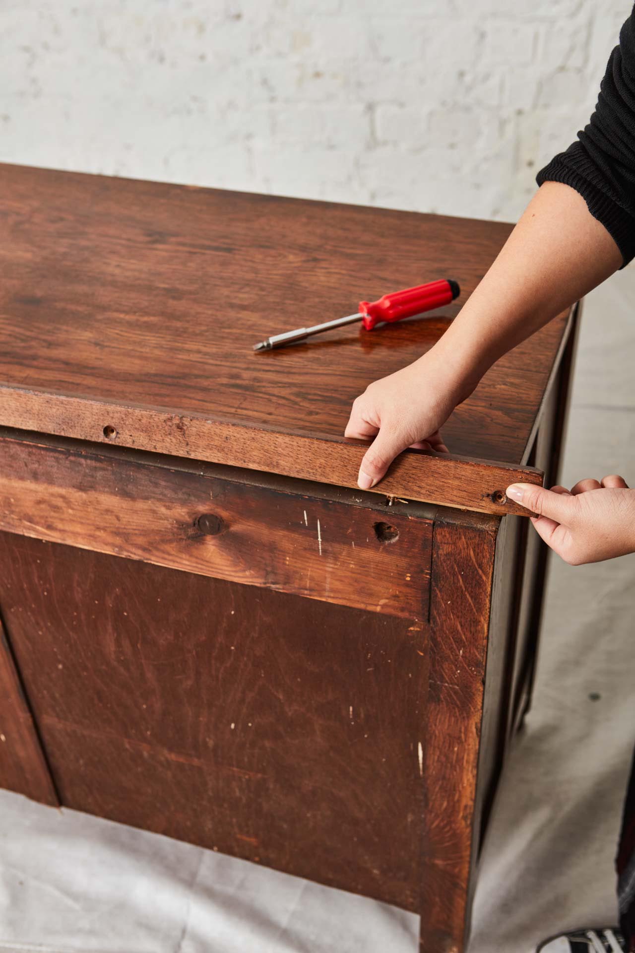 Hands removing back of a vintage chest of drawers