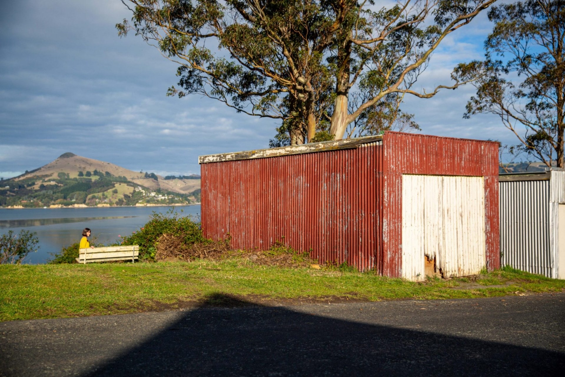 Octavia Cook sitting by lake in Port Chalmers, Dunedun