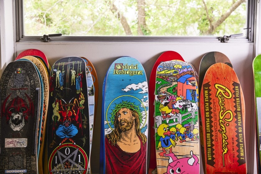 A row of skateboards with various artwork designs leaning against white wall
