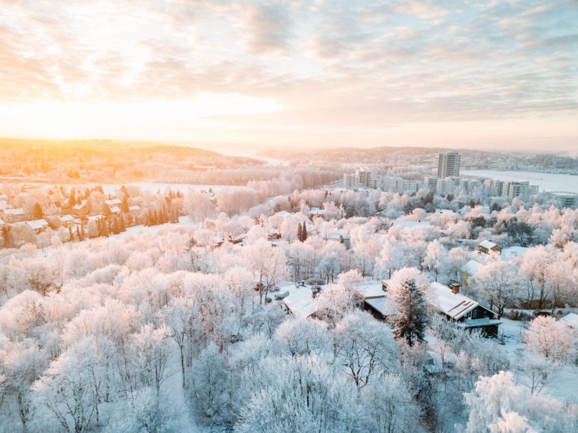 Winter landscape of a city covered in snow with sun shining in the distance