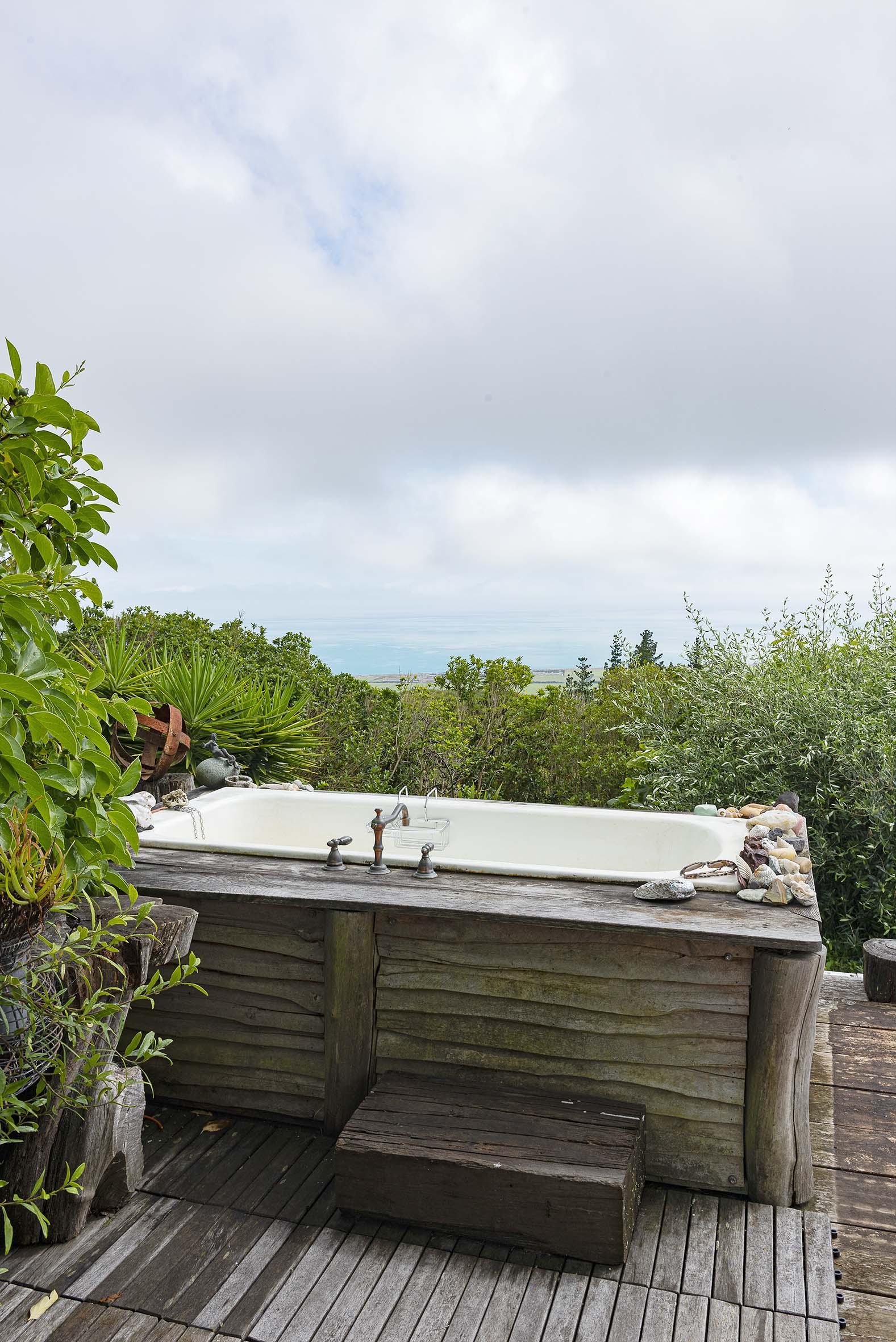 A wood outdoor bath surrounded by green plants
