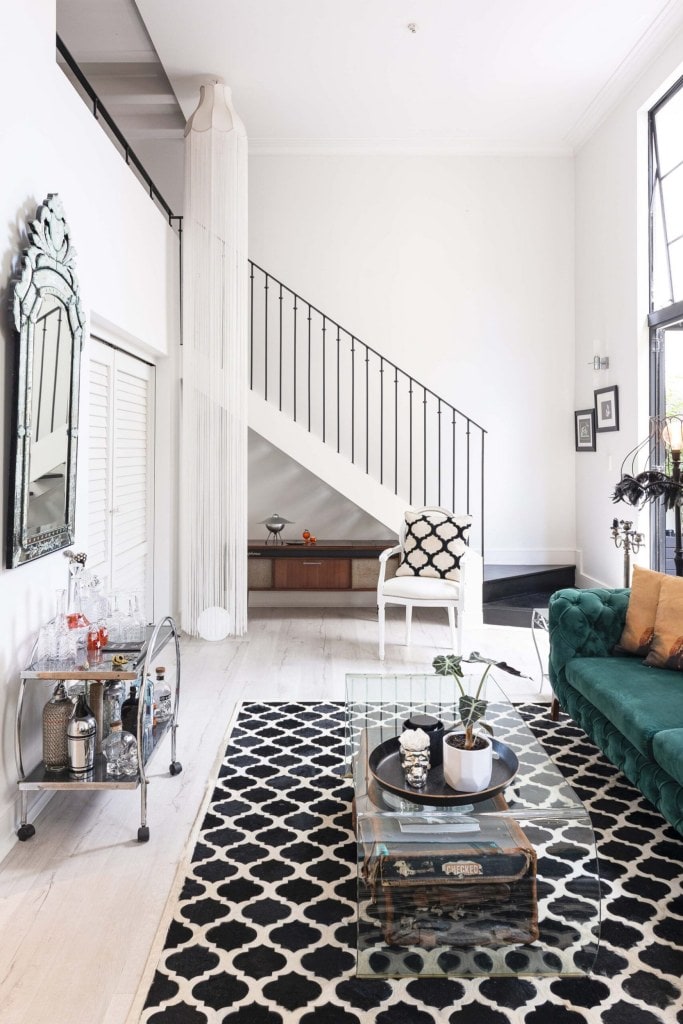 Stairway in lounge with graphic black and white rug and green couch