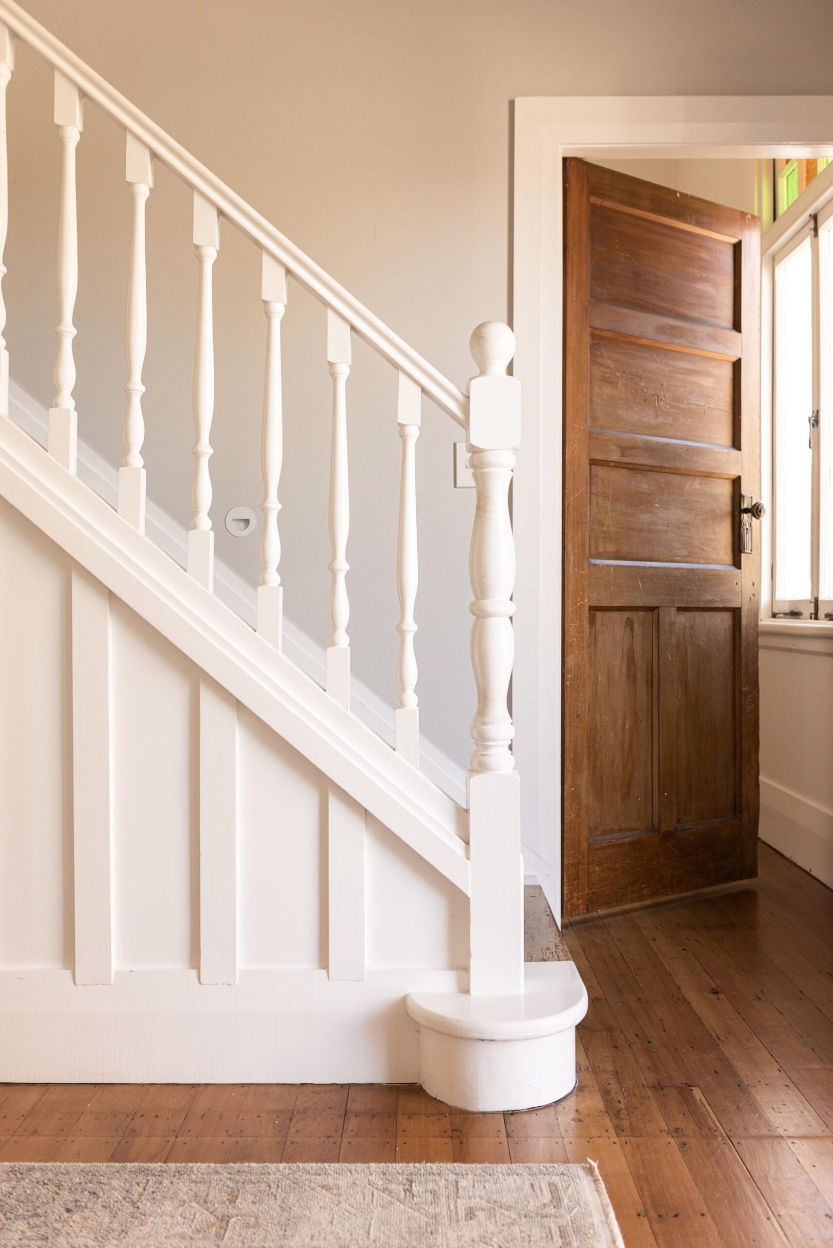 A white wood stairway in a home with polished wood floors