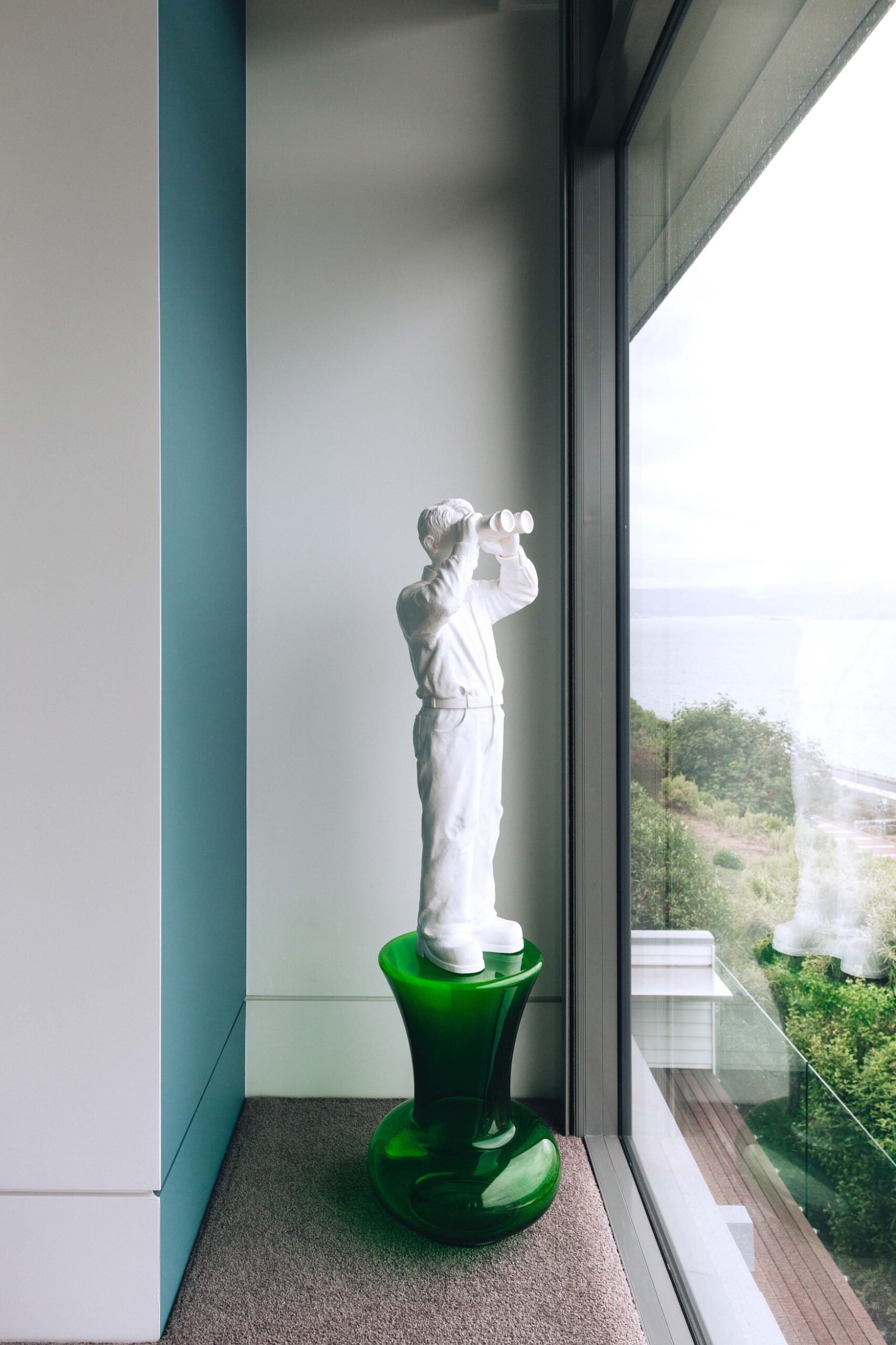 A white statue with binoculars looking out to Wellington harbour