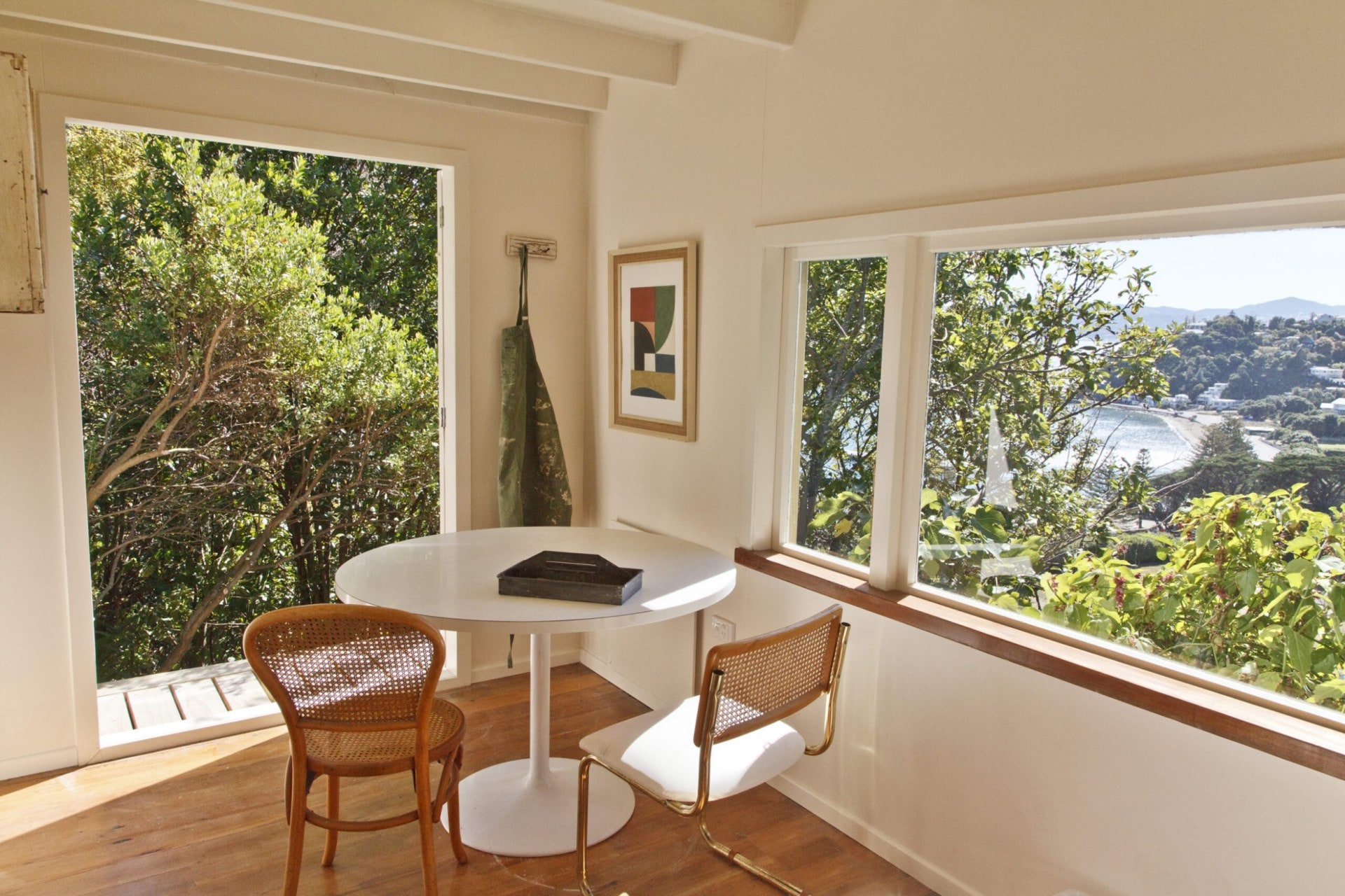 White room with open doors and large windows overlooking the Cook Strait and surrounding bush
