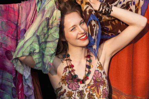 Woman smiling in the sun while holding many sarongs of different patterns