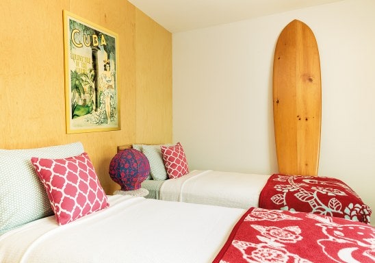 Bedroom with white beds with red duvets and beachy decorative touches