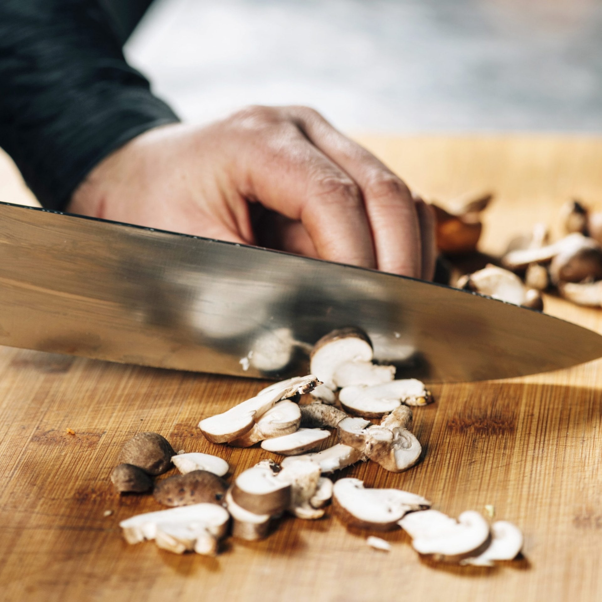 Mushrooms being chopped up with a large cooks knife