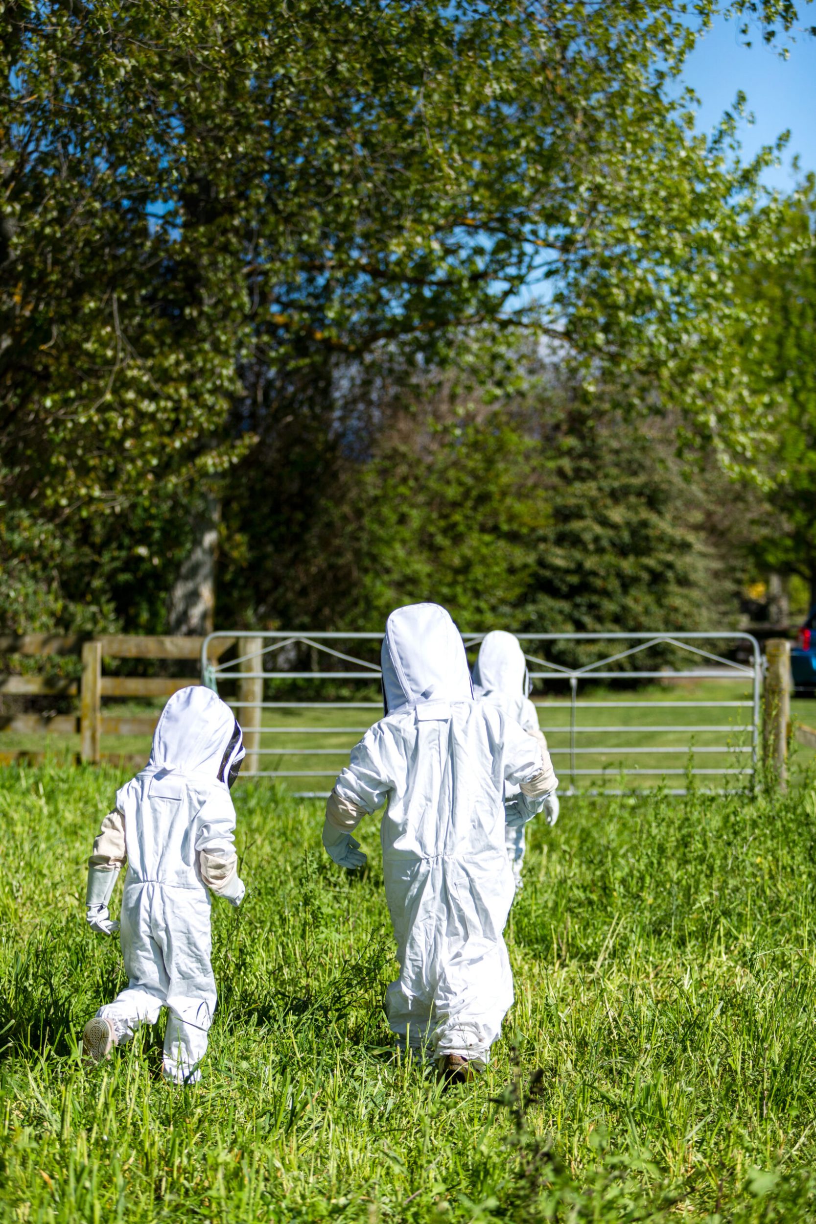 Three small children in white bee suits.