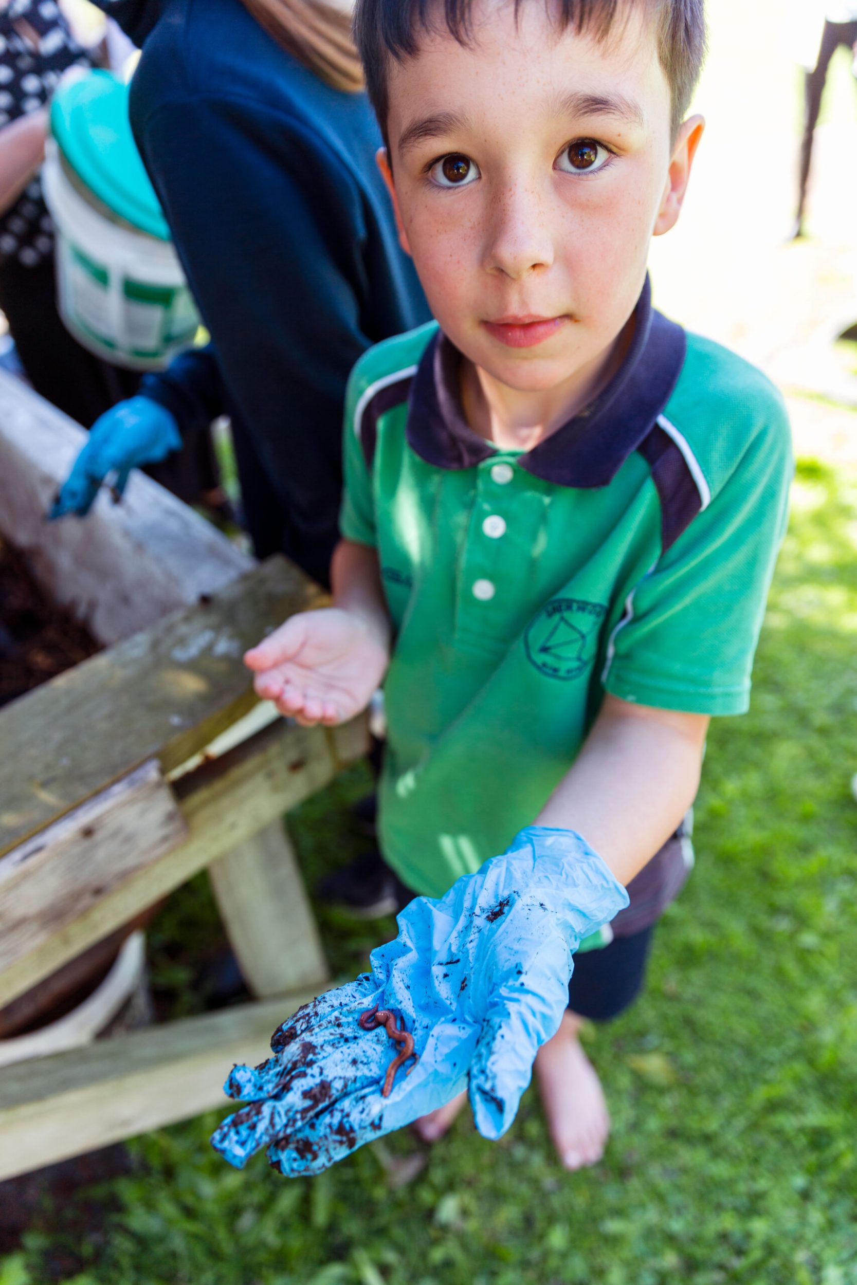 Boy wearing blue gloves holding a worm.