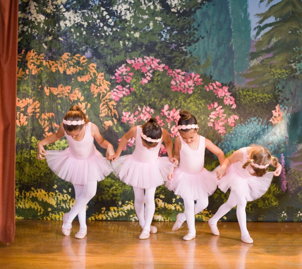 a group of little girls in pin leotards, tutus and tights and doing ballet