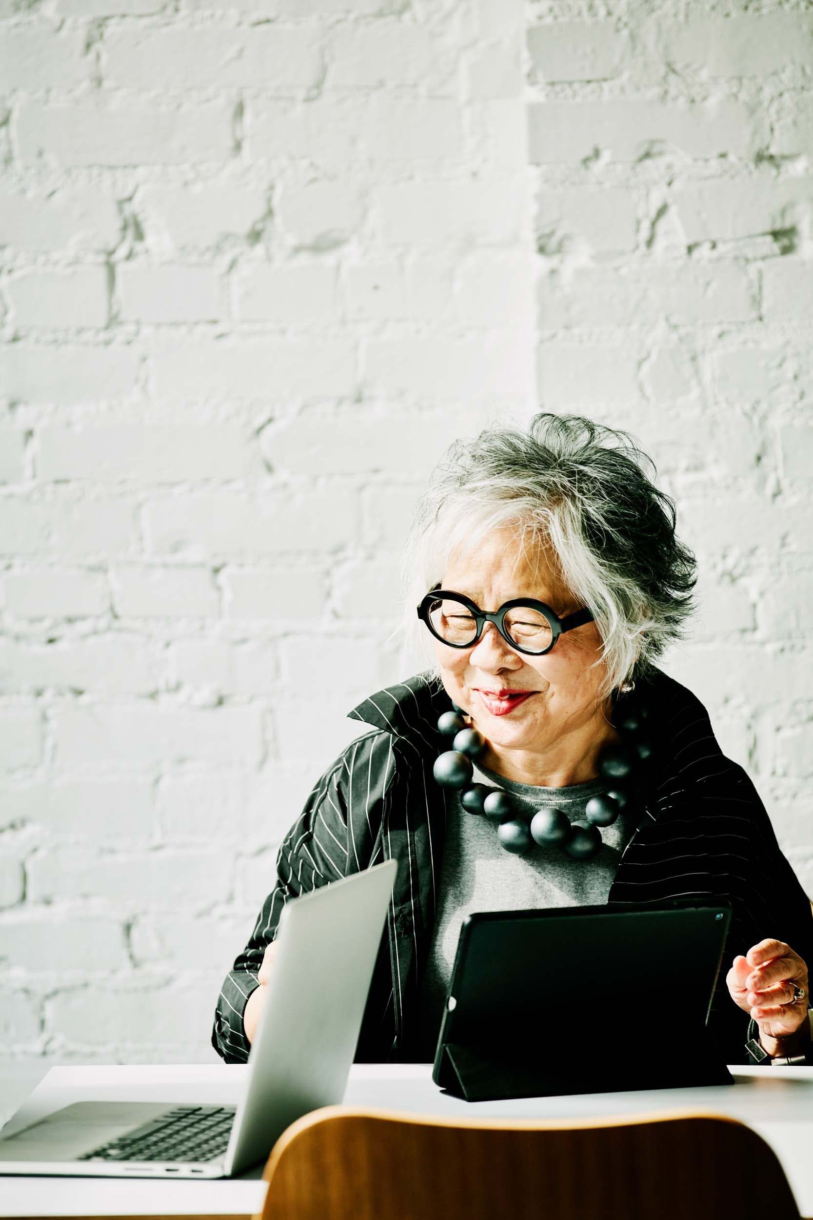 a grey haired woman sitting with a laptop