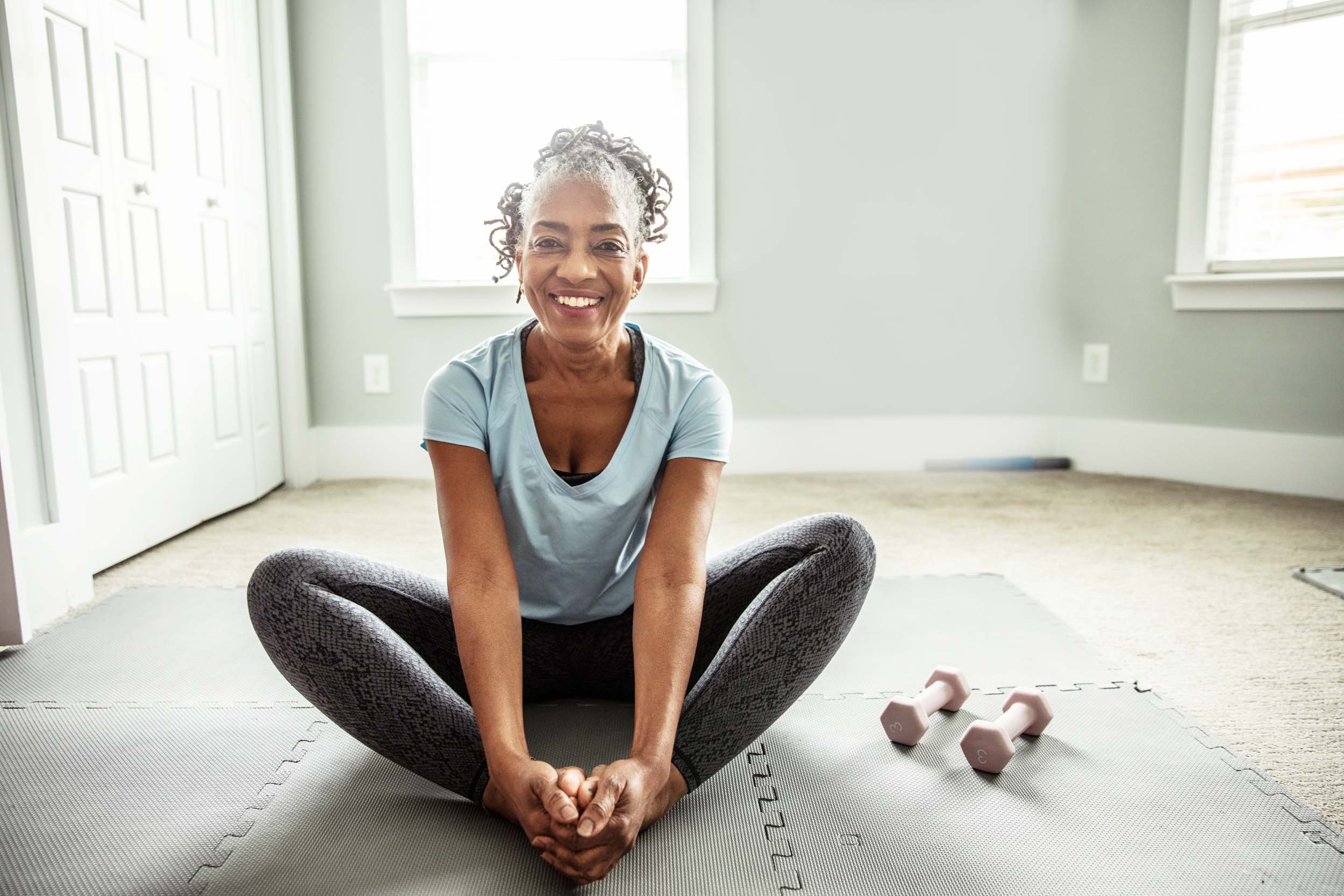 a smiling woman wearing exercise clothes sitting indoors