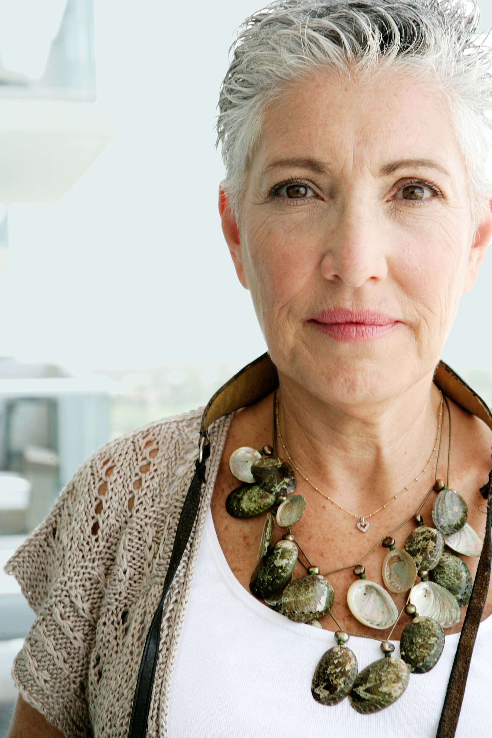a grey haired woman wearing a chunky necklace