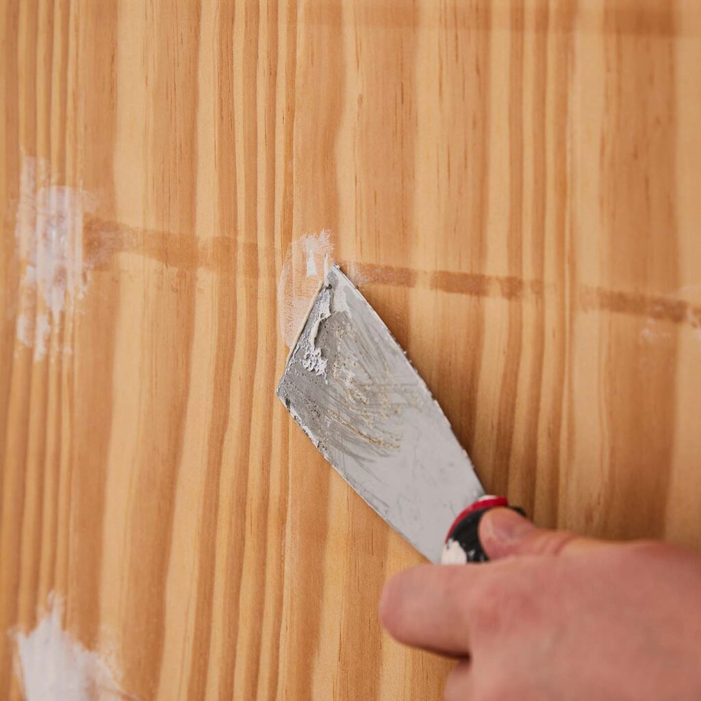 Using a putty knife to fill in any holes